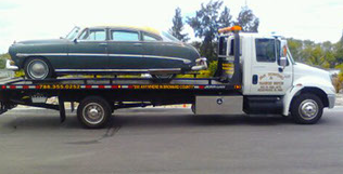 Green antique car on flatbed of J&S Towing and Transport tow truck